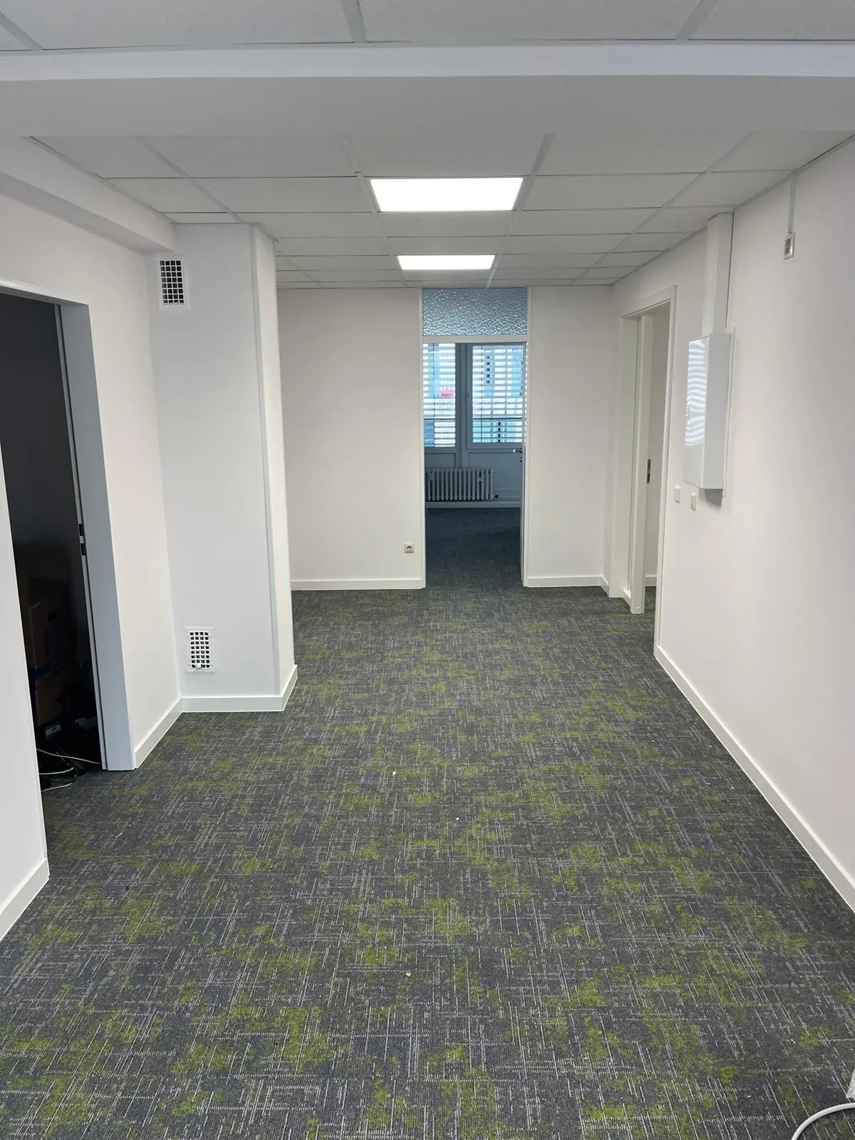 Büroflur mit verlegten Teppichfliesen und geschlossener Rasterdecke