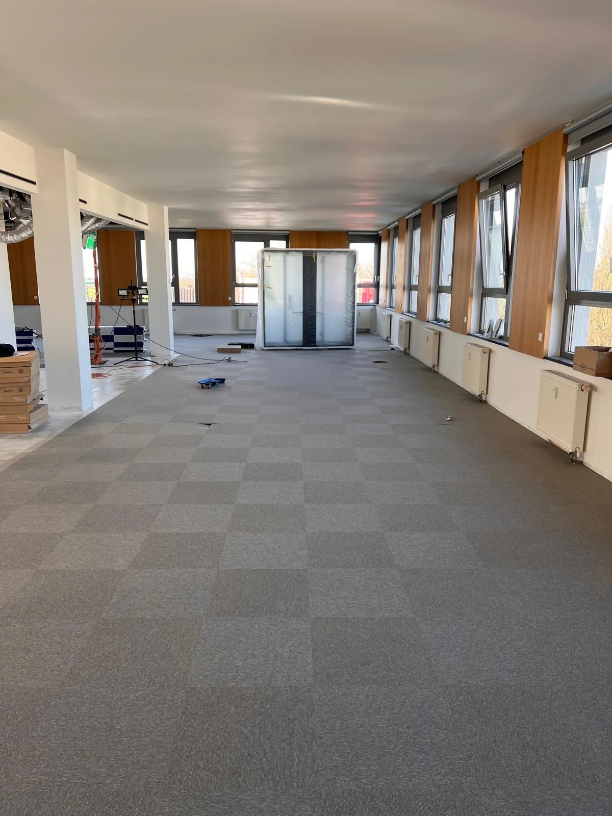 Bürofläche mit grauen Teppichfliesen und langem Fensterband