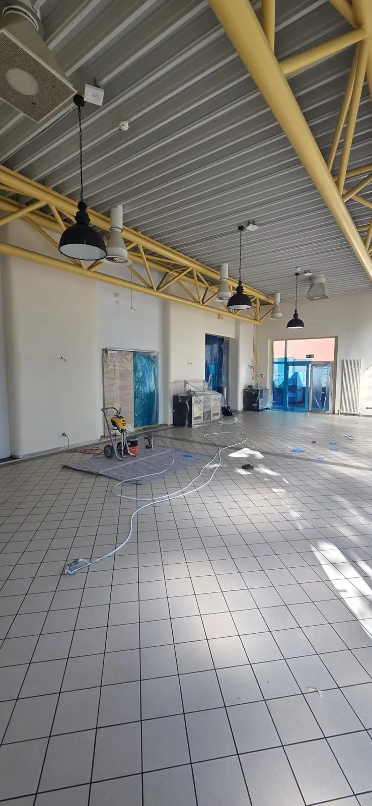 Halle während der Arbeiten mit hellem Fliesenboden und gelben Stahlträgern