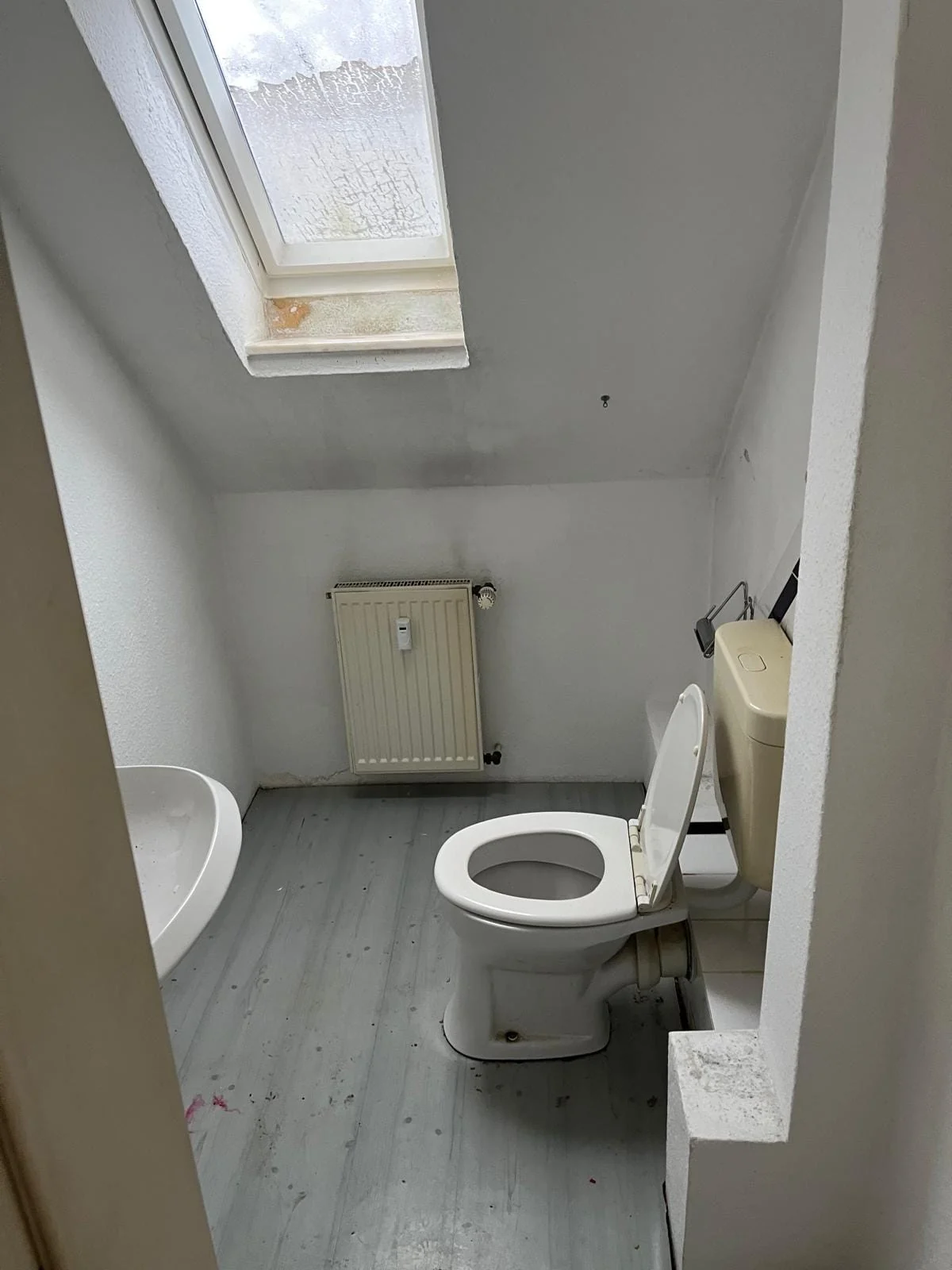 Kleiner Sanitärraum unter einer Dachschräge mit Dachfenster vor dem Umbau