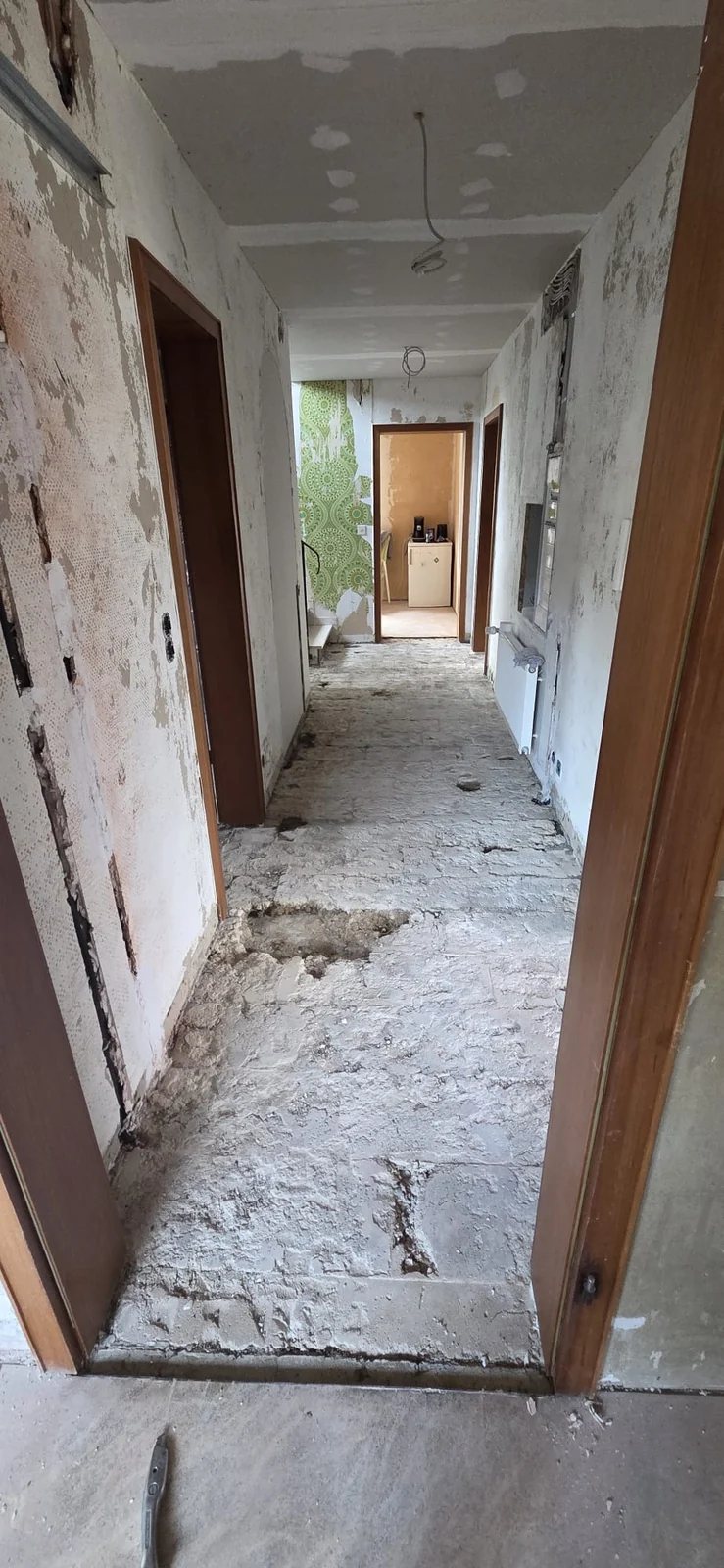 Flur während des Rückbaus mit freigelegtem Boden und offenen Wandflächen