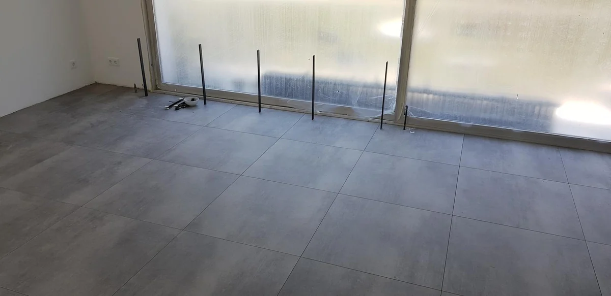 Großformatige graue Bodenfliesen während der Arbeiten vor einer geschützten Glasfront