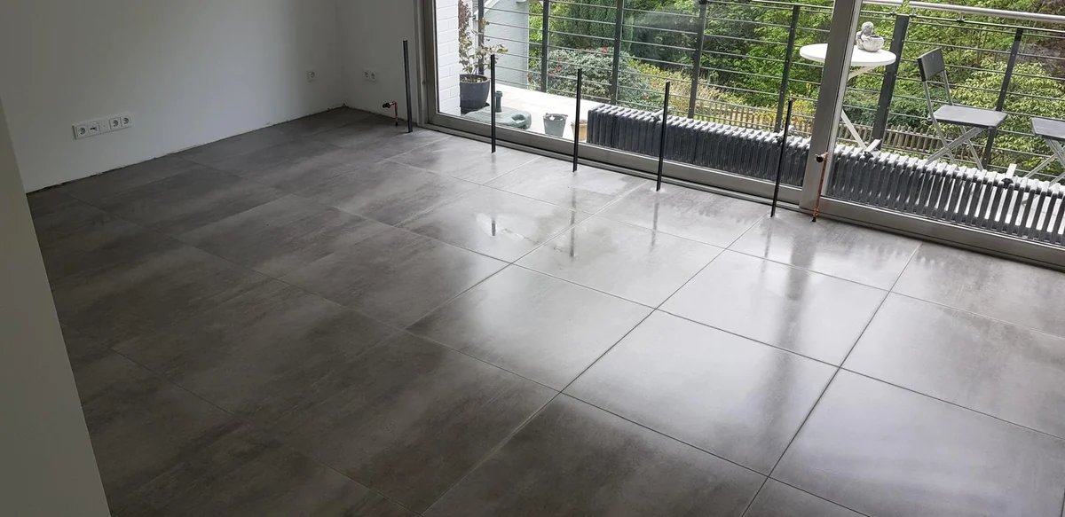 Großformatige graue Bodenfliesen vor einer bodentiefen Glasfront